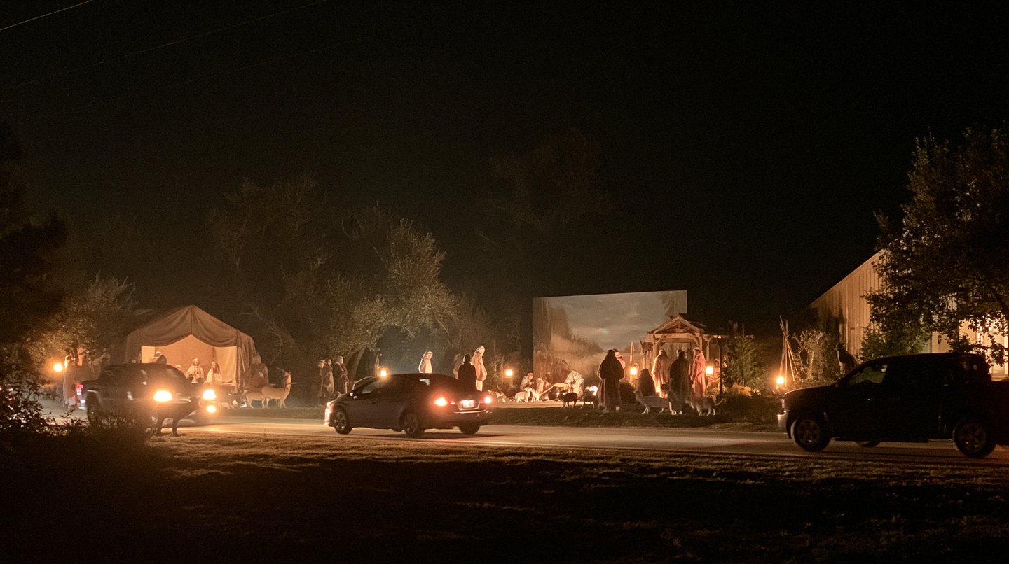 Cars moving slowly past a lantern-lit scene on the route